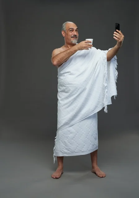 رجل سعودي بملابس الإحرام يلتقط سيلفي بالهاتف