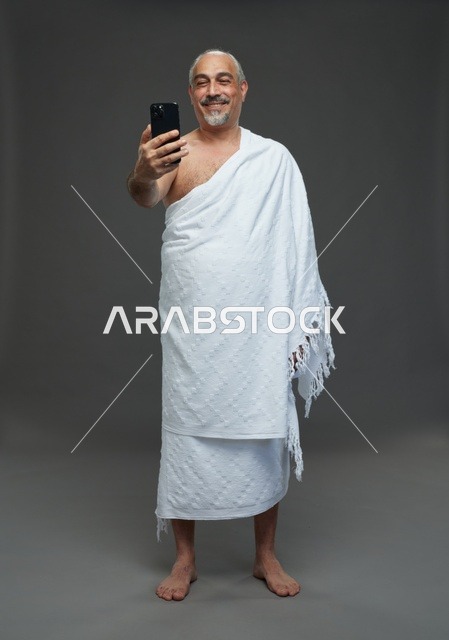 رجل سعودي بملابس الإحرام يلتقط سيلفي بالهاتف