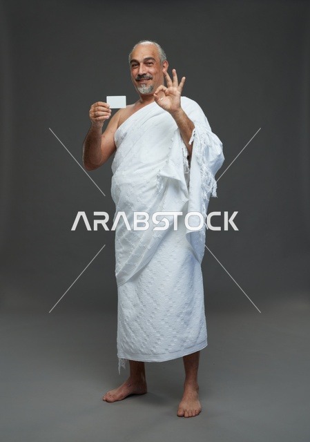 رجل سعودي بملابس الإحرام يحمل بطاقة بيضاء فارغة
