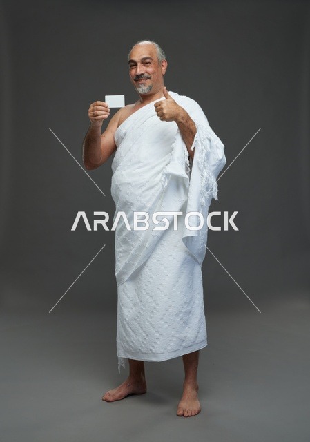 رجل سعودي بملابس الإحرام يحمل بطاقة فارغة للإعلان