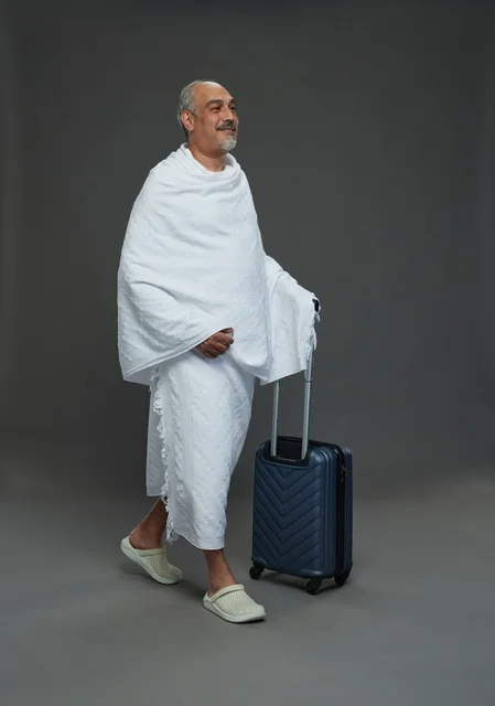 رجل سعودي بملابس الإحرام مع حقيبة سفر