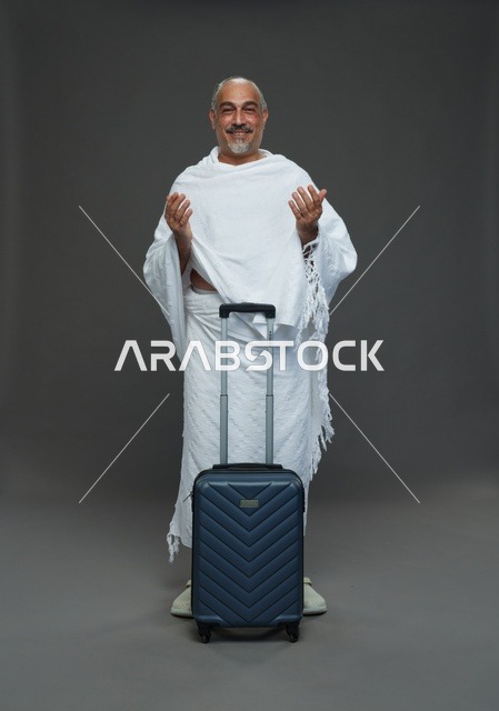 رجل سعودي بملابس الإحرام مع حقيبة سفر يدعو للحج