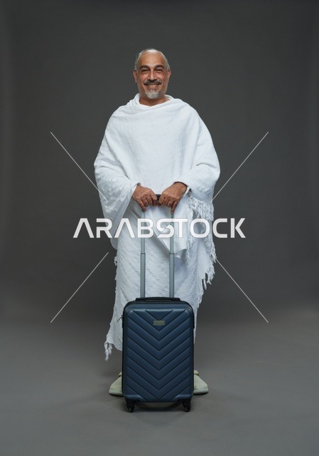 رجل سعودي بملابس الإحرام وحقيبة سفر لرحلة الحج والعمرة