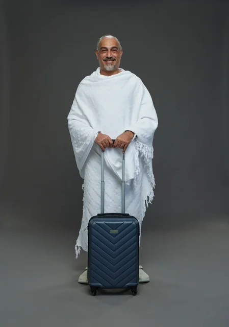 رجل سعودي بملابس الإحرام وحقيبة سفر لرحلة الحج والعمرة