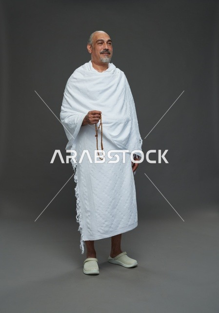 رجل سعودي بملابس الإحرام يمسك مسبحة في الاستوديو