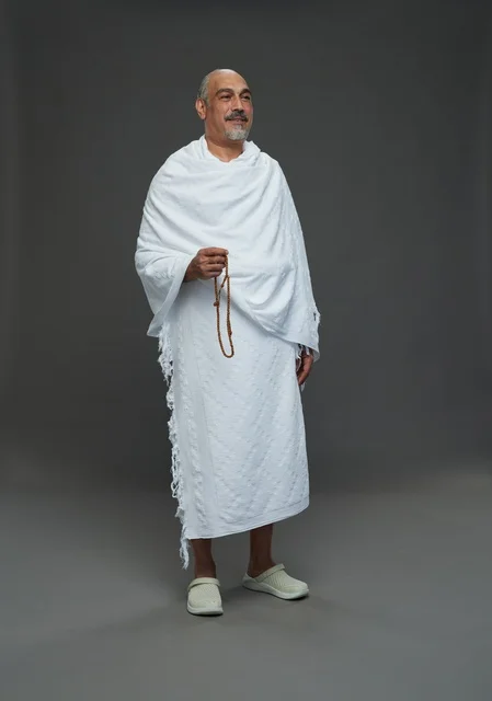 رجل سعودي بملابس الإحرام يمسك مسبحة في الاستوديو