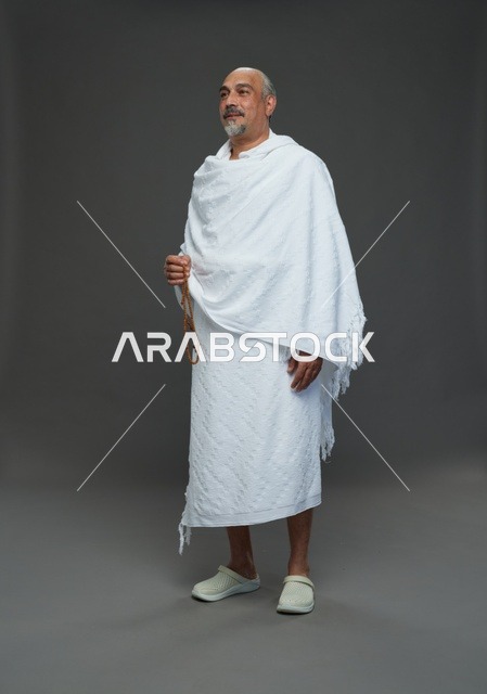 رجل سعودي بملابس الإحرام يمسك مسبحة في الاستوديو