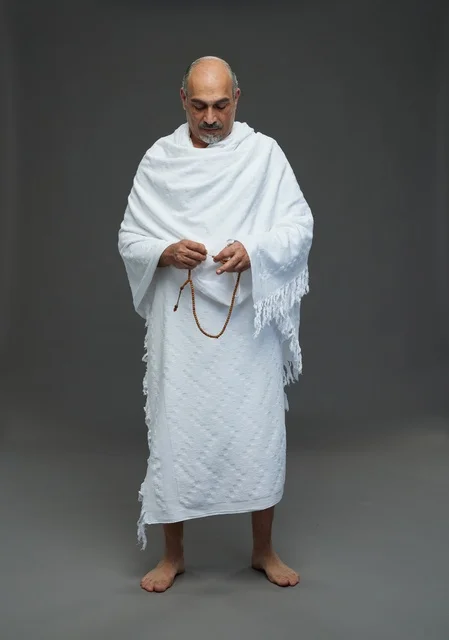 رجل سعودي بملابس الإحرام يمسك مسبحة في الاستوديو