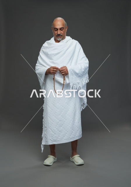 رجل سعودي بملابس الإحرام يمسك مسبحة في الاستوديو