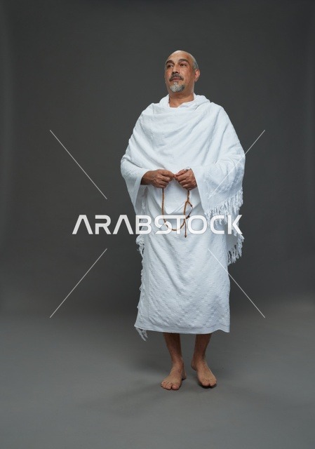 رجل سعودي بملابس الإحرام يحمل مسبحة في استوديو