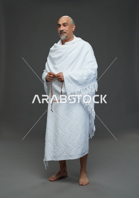 رجل سعودي بملابس الإحرام يمسك مسبحة في الاستوديو