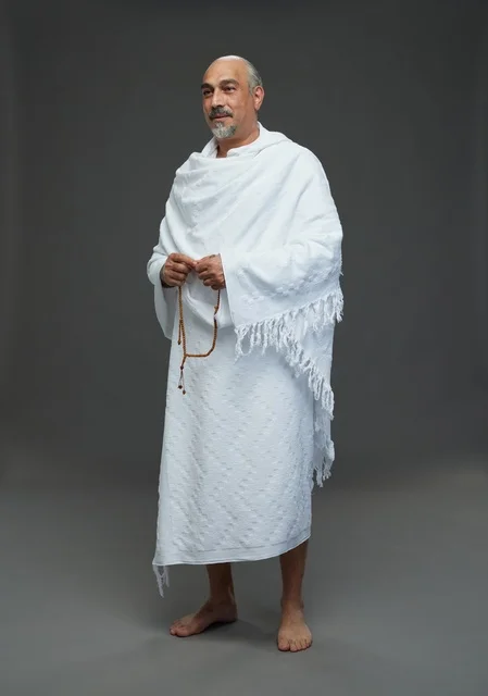 رجل سعودي بملابس الإحرام يمسك مسبحة في الاستوديو