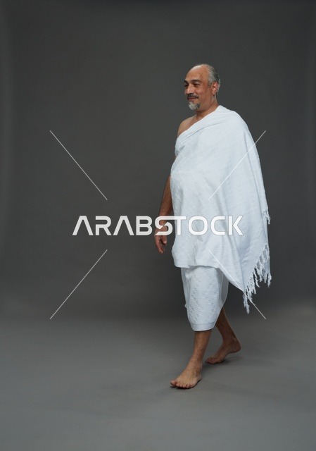 Saudi Man in Ihram Walking on Gray Background