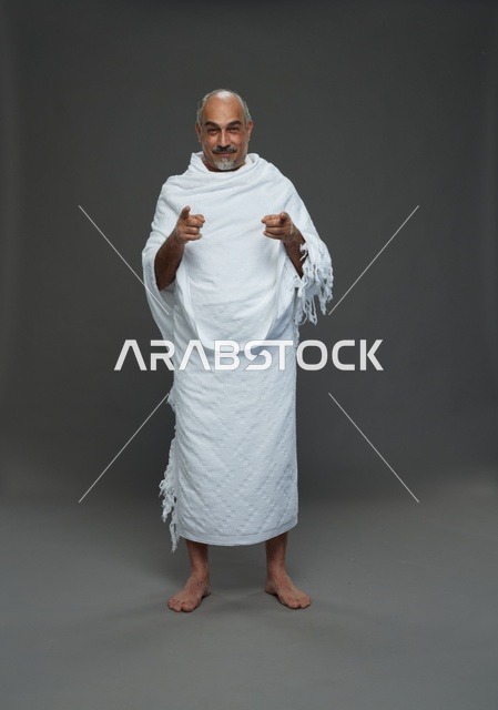 رجل سعودي بملابس الإحرام يشير للأمام في الاستوديو