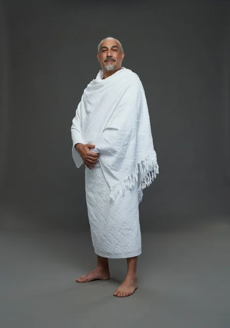 رجل سعودي مبتسم بملابس الإحرام لأداء مناسك الحج والعمرة