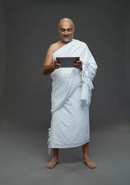 رجل سعودي بملابس الإحرام يستخدم جهازًا لوحيًا