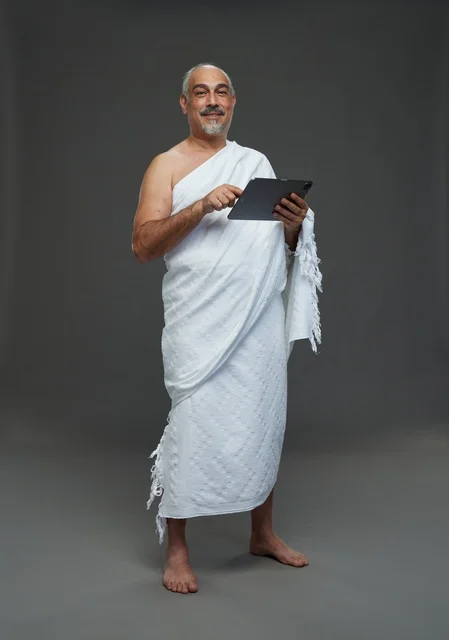 رجل سعودي بملابس الإحرام يستخدم جهازاً لوحياً