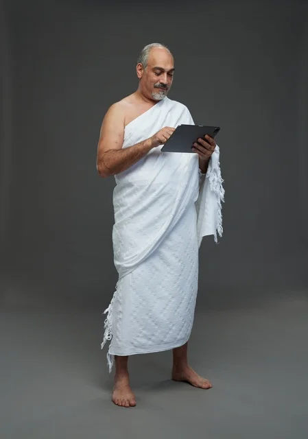 Saudi Man in Ihram Using Tablet on Gray Background