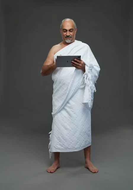 رجل سعودي بملابس الإحرام يستخدم جهازاً لوحياً