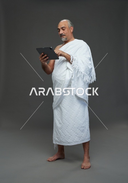 رجل سعودي بملابس الإحرام يستخدم تابلت في استوديو