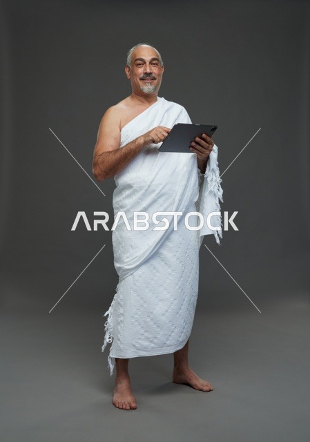 رجل سعودي بملابس الإحرام يستخدم جهاز تابلت في استوديو