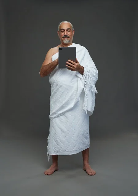 Saudi Man in Ihram Using Tablet on Grey Background