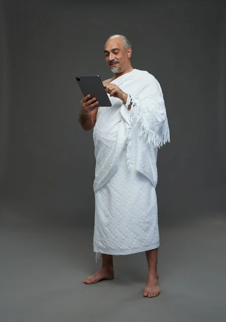 Saudi Man in Ihram Using Tablet on Gray Background