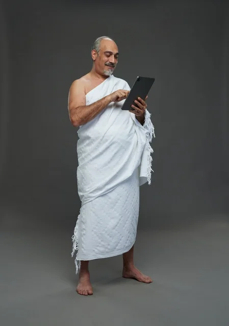 رجل سعودي بملابس الإحرام يستخدم جهازاً لوحياً