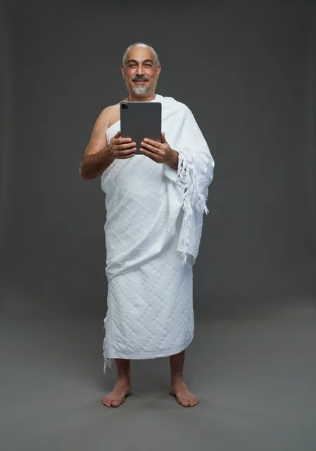رجل سعودي بملابس الإحرام يستخدم جهازًا لوحيًا