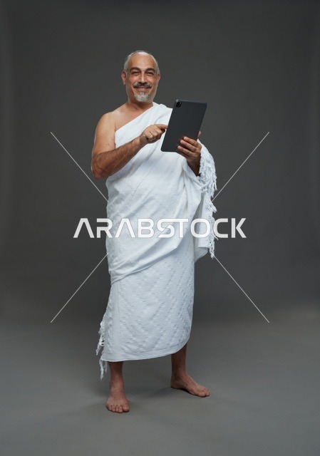 رجل سعودي بملابس الإحرام يستخدم جهاز لوحي