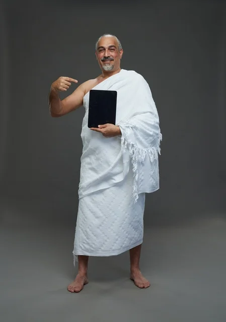 Saudi Man in Ihram Holding Tablet on Grey Background