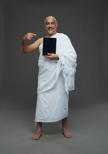 Saudi Man in Ihram Attire Pointing at Digital Tablet