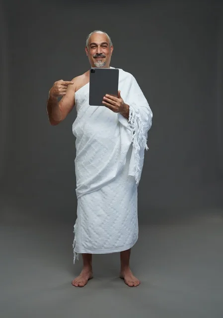 Saudi Man in Ihram Using Tablet on Gray Background