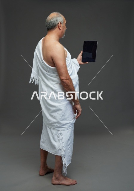 رجل سعودي بملابس الإحرام يستخدم تابلت