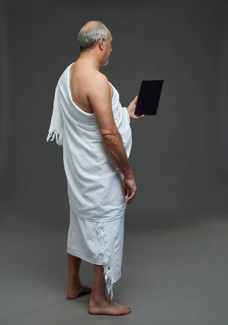 رجل سعودي بملابس الإحرام يستخدم جهازاً لوحياً