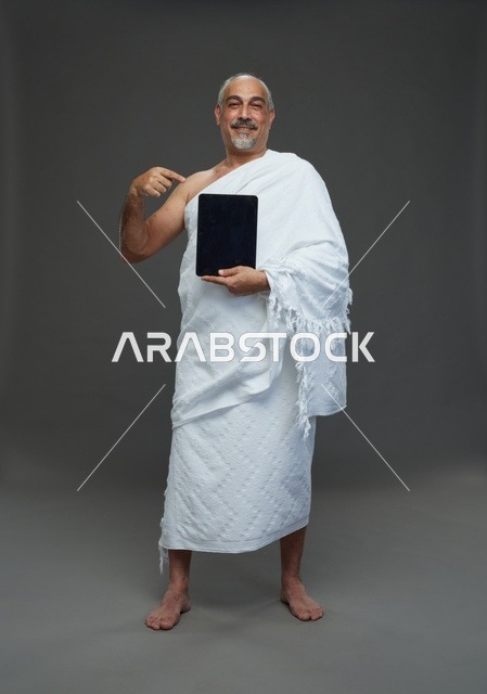 رجل سعودي بملابس الإحرام مع تابلت في استوديو