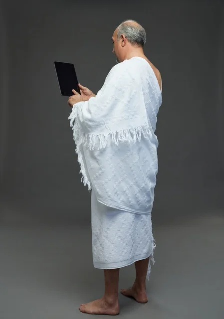 رجل سعودي بملابس الإحرام يستخدم جهازاً لوحياً في الاستوديو