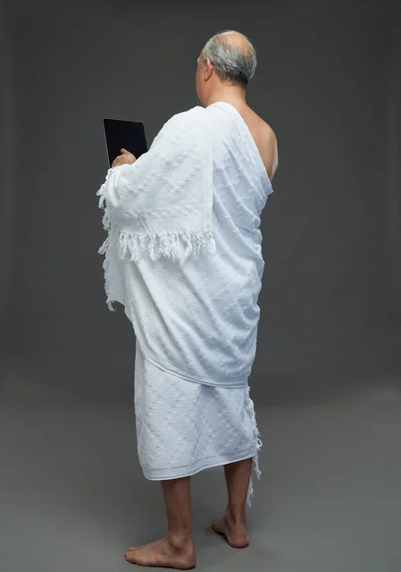 Saudi Man in Ihram Using Tablet on Grey Background
