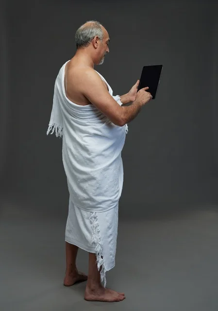 رجل سعودي بملابس الإحرام يستخدم جهازاً لوحياً