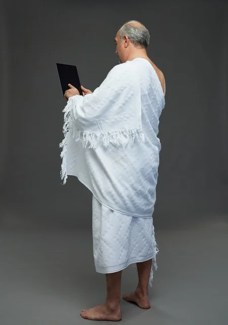 رجل سعودي بملابس الإحرام يستخدم جهازاً لوحياً