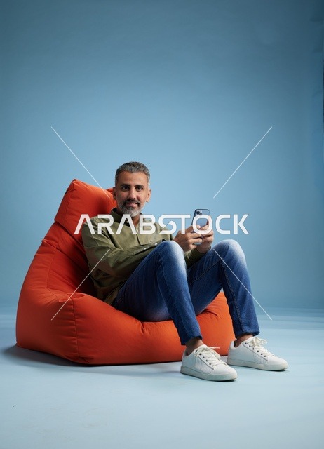Saudi Man Using Smartphone on Orange Beanbag Chair