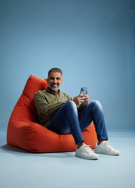 Saudi Man with Smartphone on Orange Beanbag Studio Shot