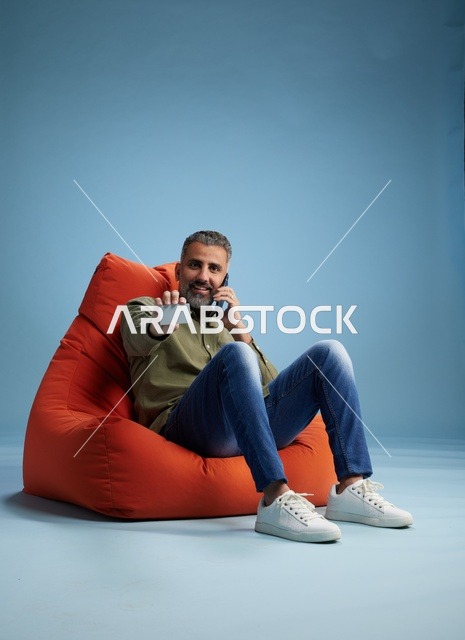 رجل سعودي يحمل بطاقة ائتمان وهاتف على مقعد محشو