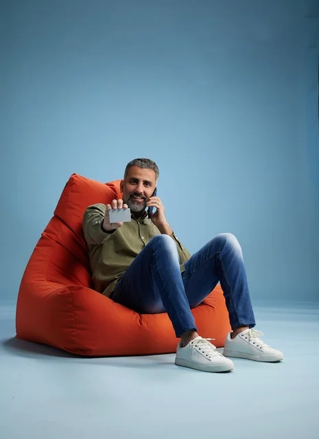 رجل سعودي يحمل بطاقة ائتمان وهاتف على مقعد محشو