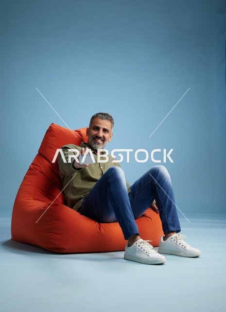 رجل سعودي يحمل بطاقة ائتمان على كرسي بين باج