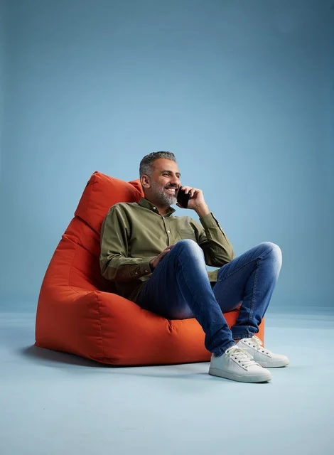 Saudi Man Talking on Smartphone in Orange Beanbag Chair