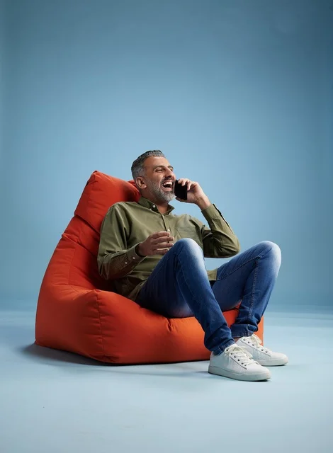 Saudi Man Laughing on Smartphone Against Blue Background