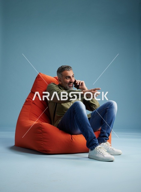 رجل سعودي يتحدث بالهاتف جالساً على بين باج