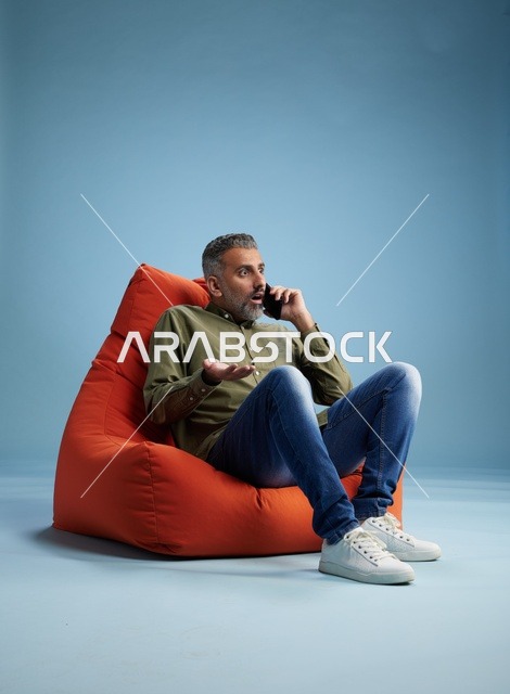 رجل سعودي متفاجئ يتحدث بالهاتف على مقعد محشو