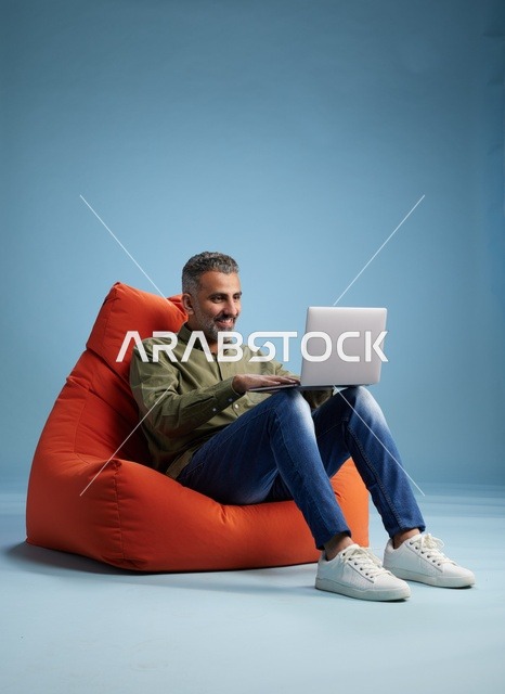 رجل سعودي يعمل على لابتوب في كرسي مريح